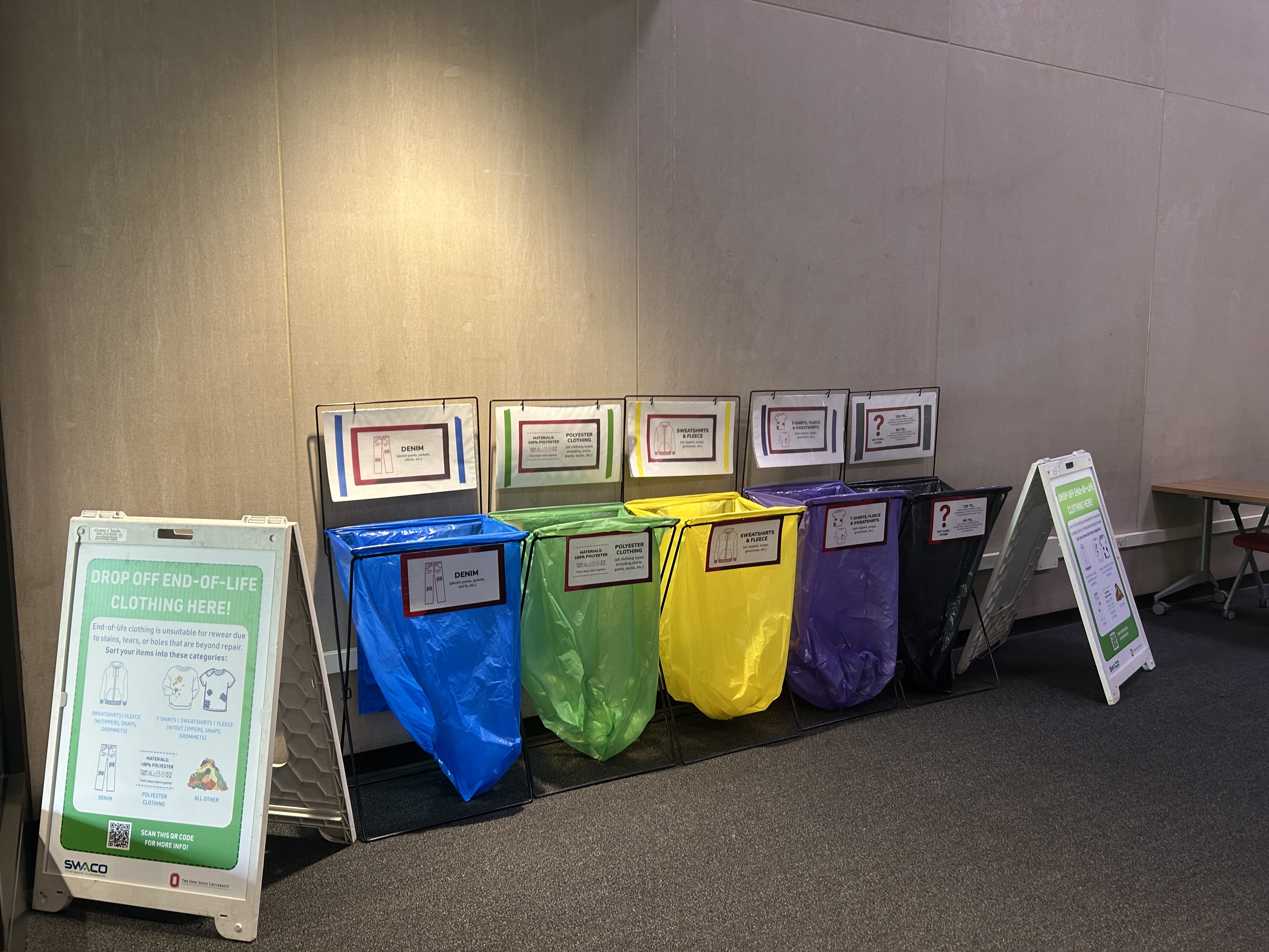 A blue, green, yellow, purple and black recycle bin for clothing.