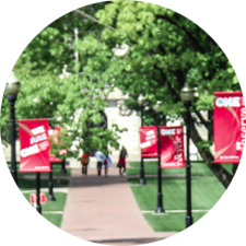 A path on campus with banner signs hanging from light poles.