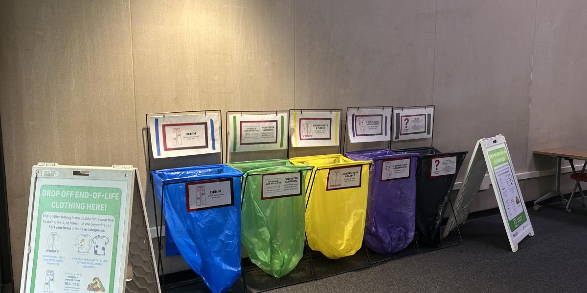 A blue, green, yellow, purple and black recycle bin for clothing.