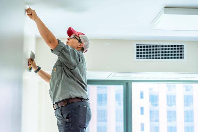 A person is seen painting the top of a wall