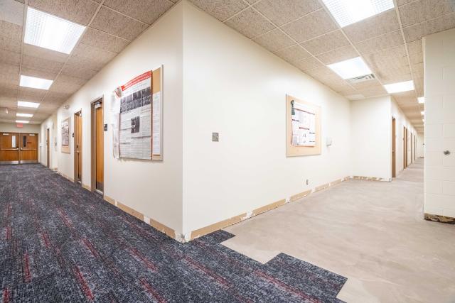 The corner of a hallway with carpet on the left and no carpet on the right.