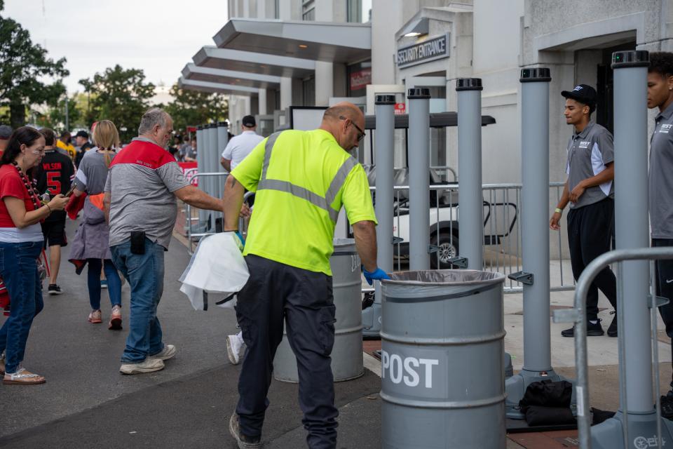 A man wearing a high visibility vest checking a trash bin.