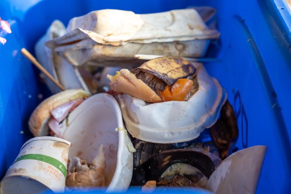 A view of a recycling bin where trash and a banana peel are seen.