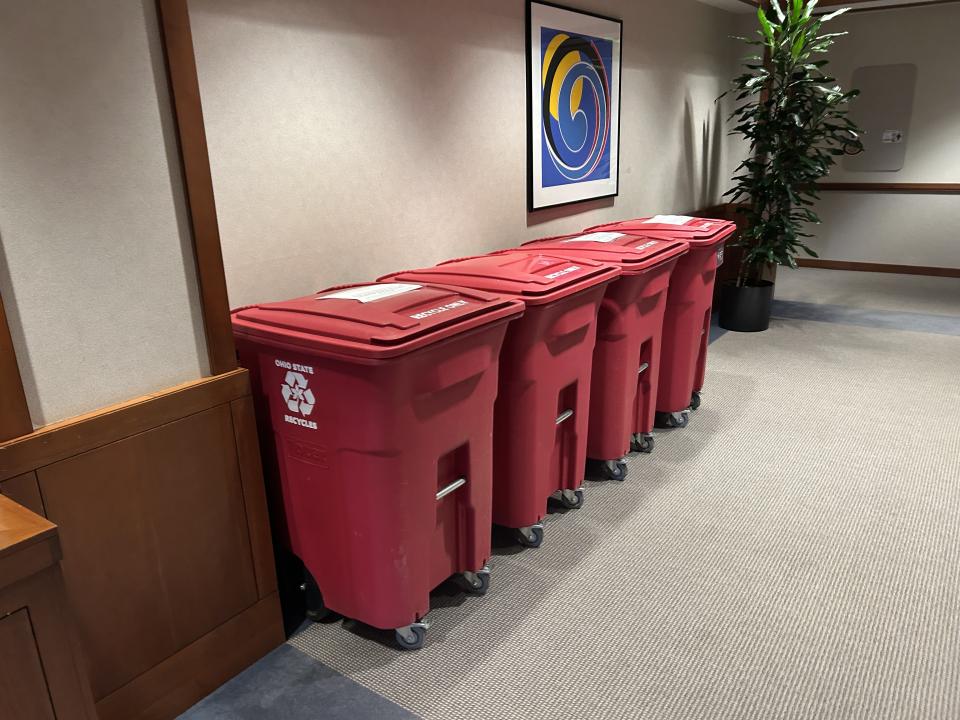 Four red recycle bins lined up against a wall