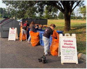 A woman is seen using the garden plastic recycling bins.